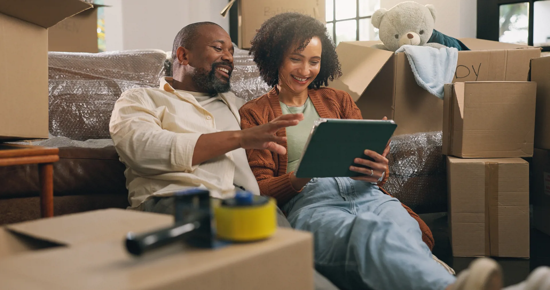 Boxes, relax and tablet with African couple in new home together for planning or property investment.