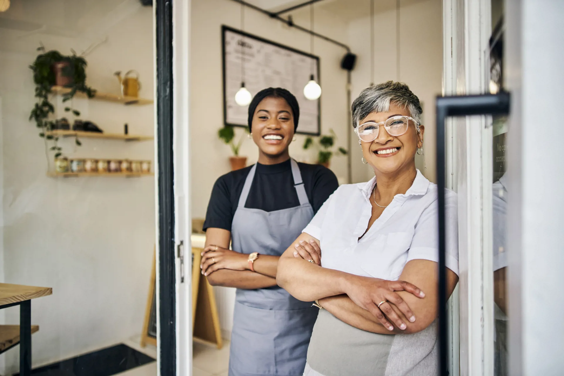 Coffee shop owner and barista smiling in front of a café