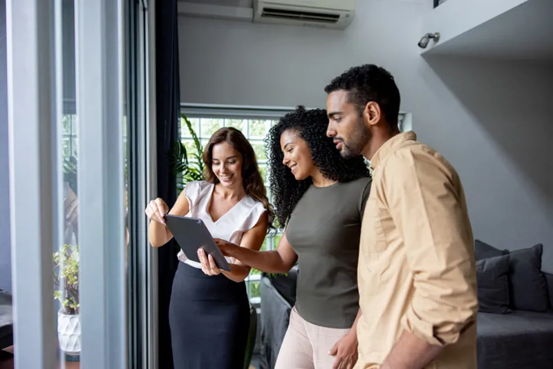 Couple looking at the details of a house on a tablet at a real estate showing