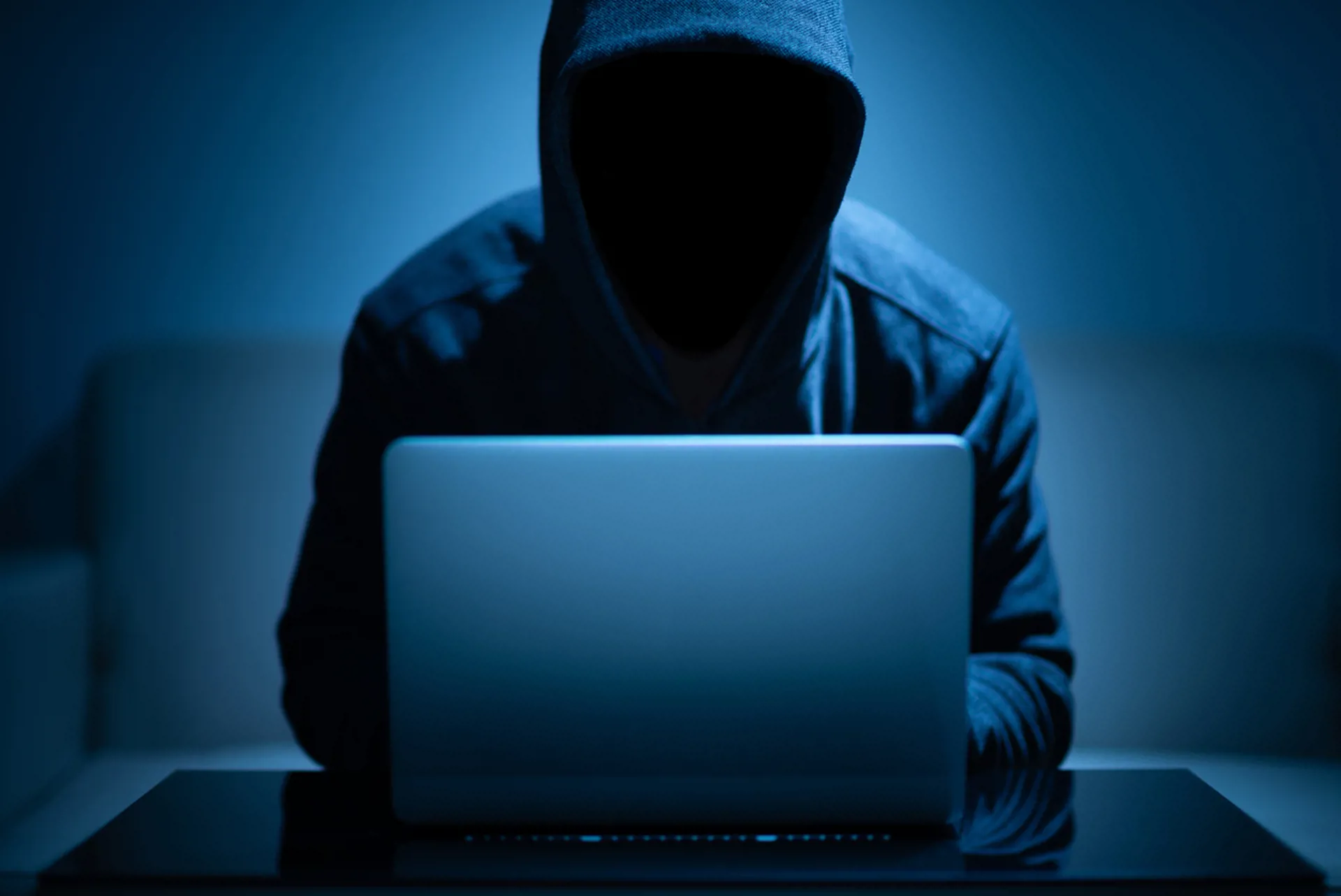 Hacker dark face using laptop