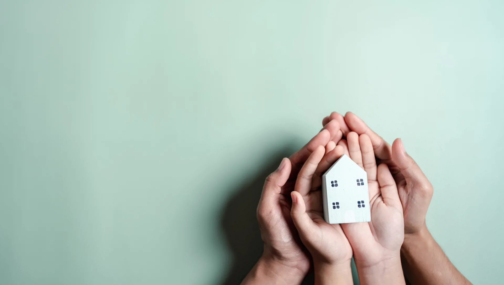 Hands holding wooden house