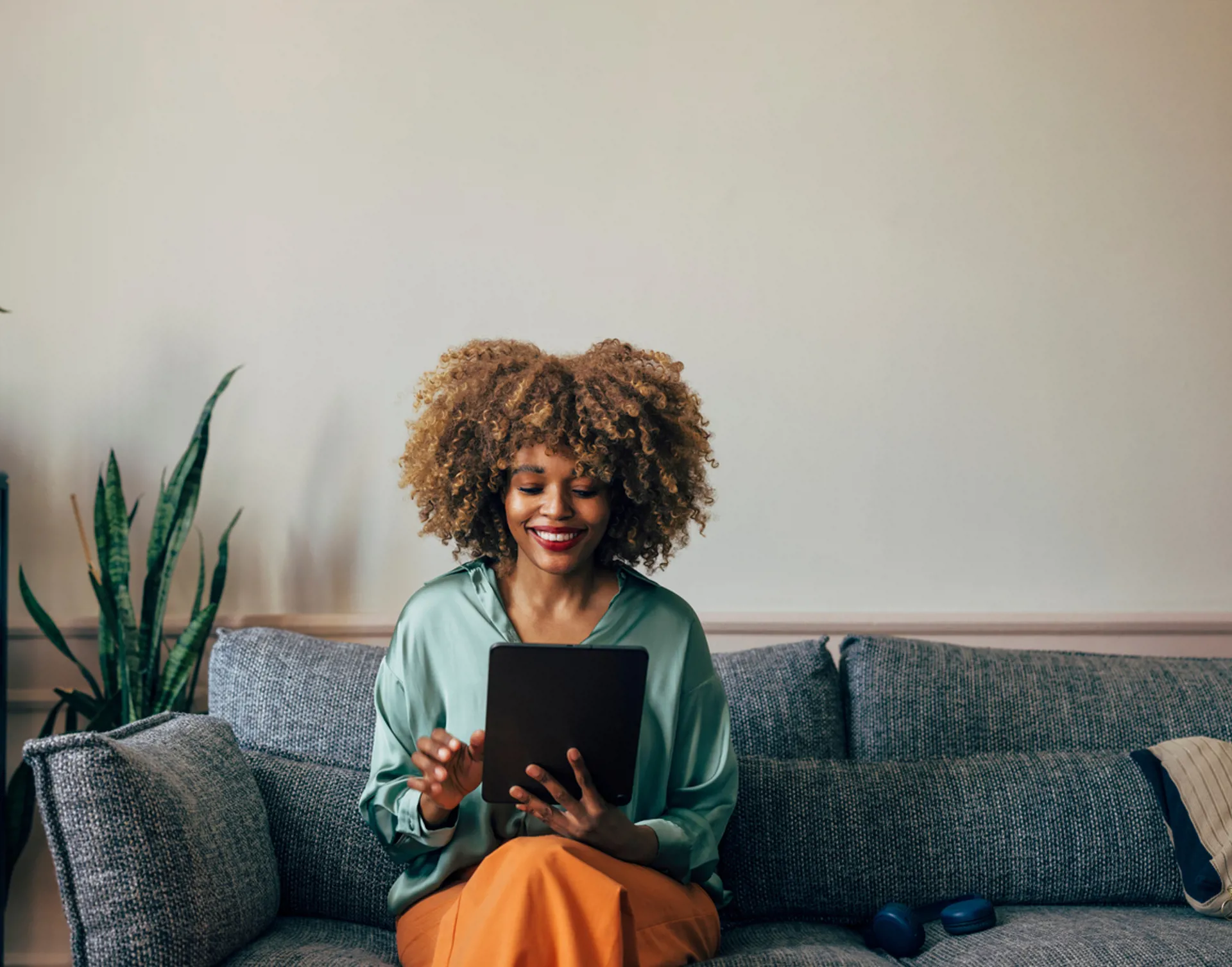 Happy African American Woman Using Tablet on a Cozy Sofa at Home