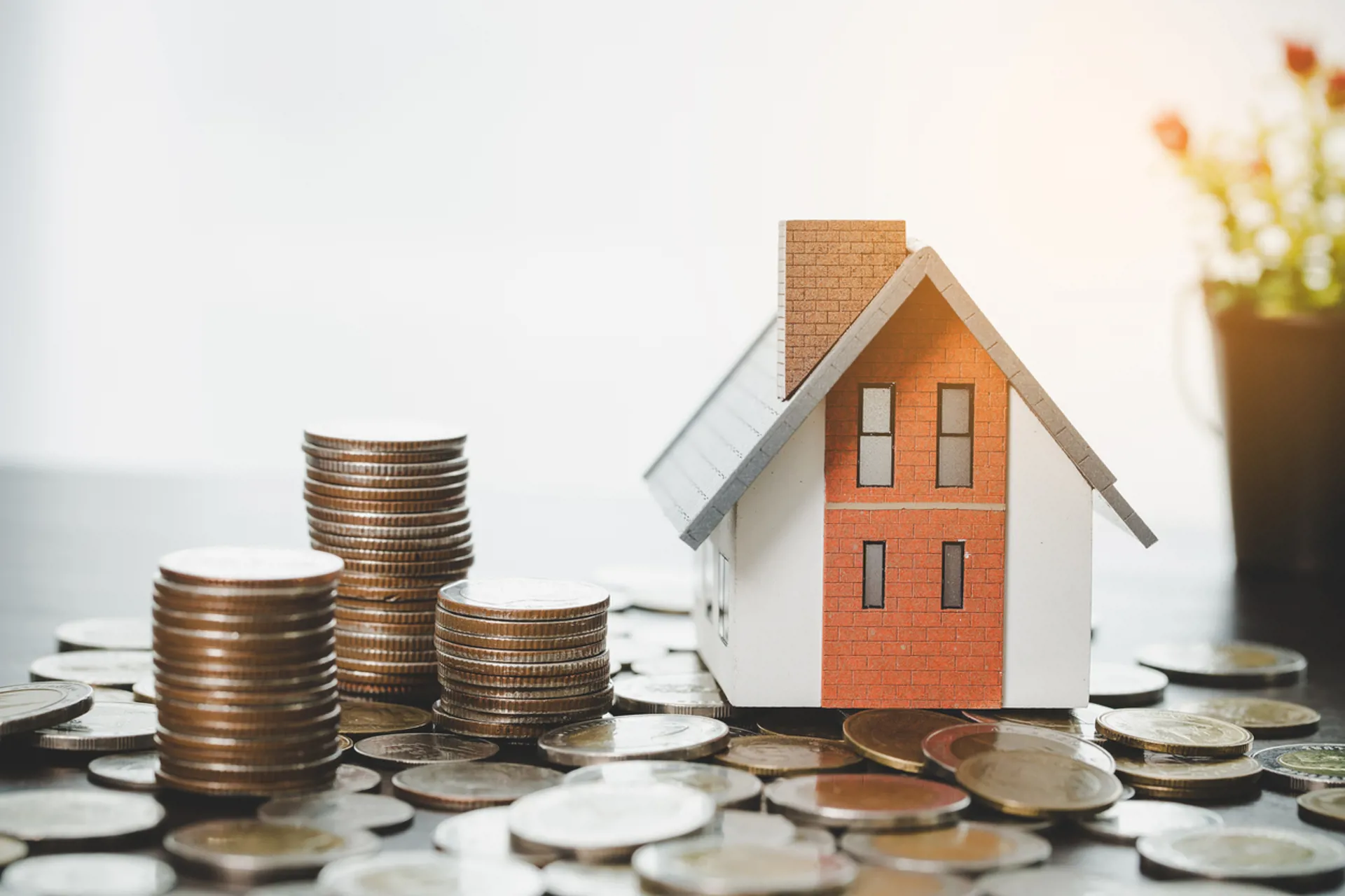House model and money coins stacks on blur table background