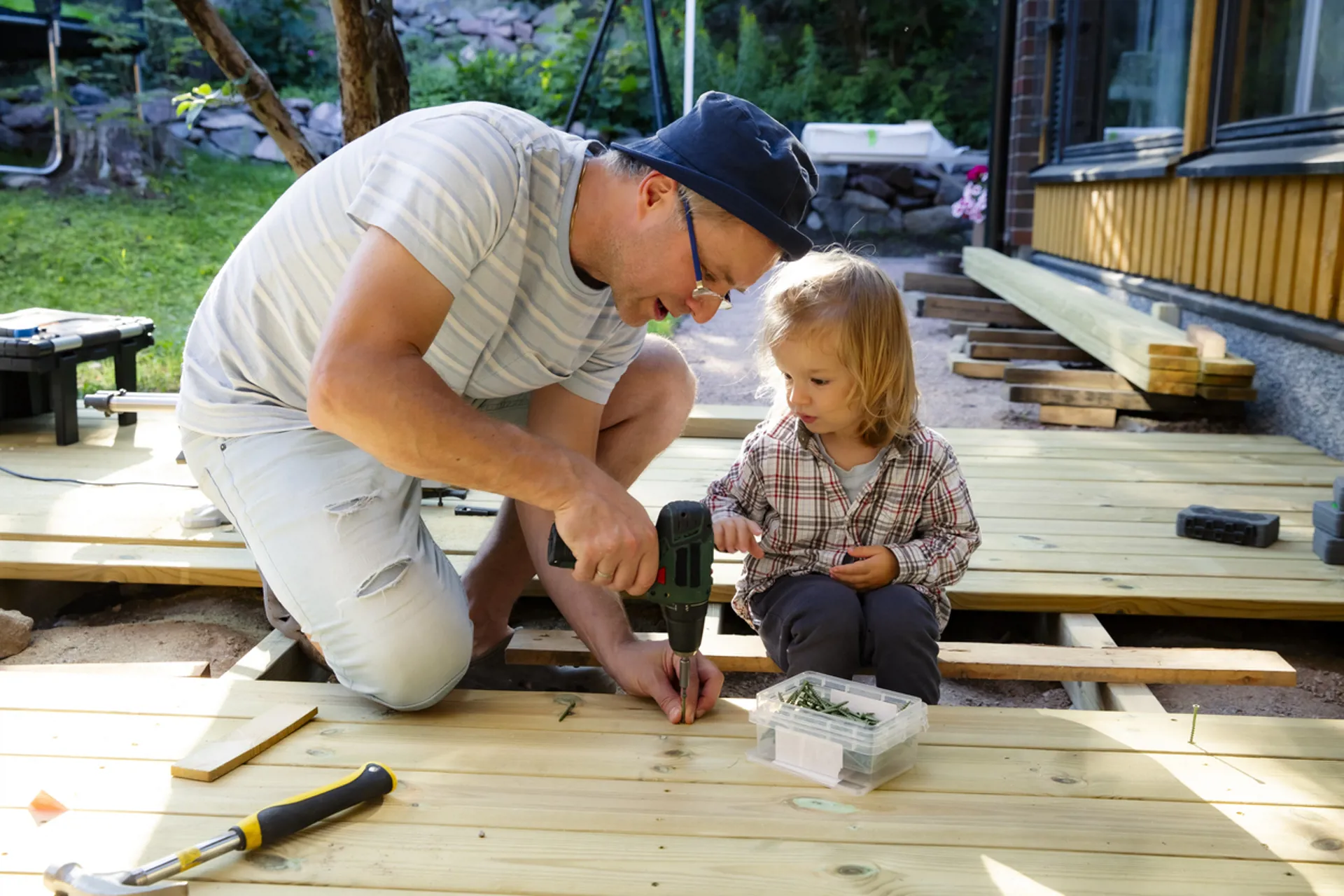 Joyful father and daughter building a wooden patio deck together.