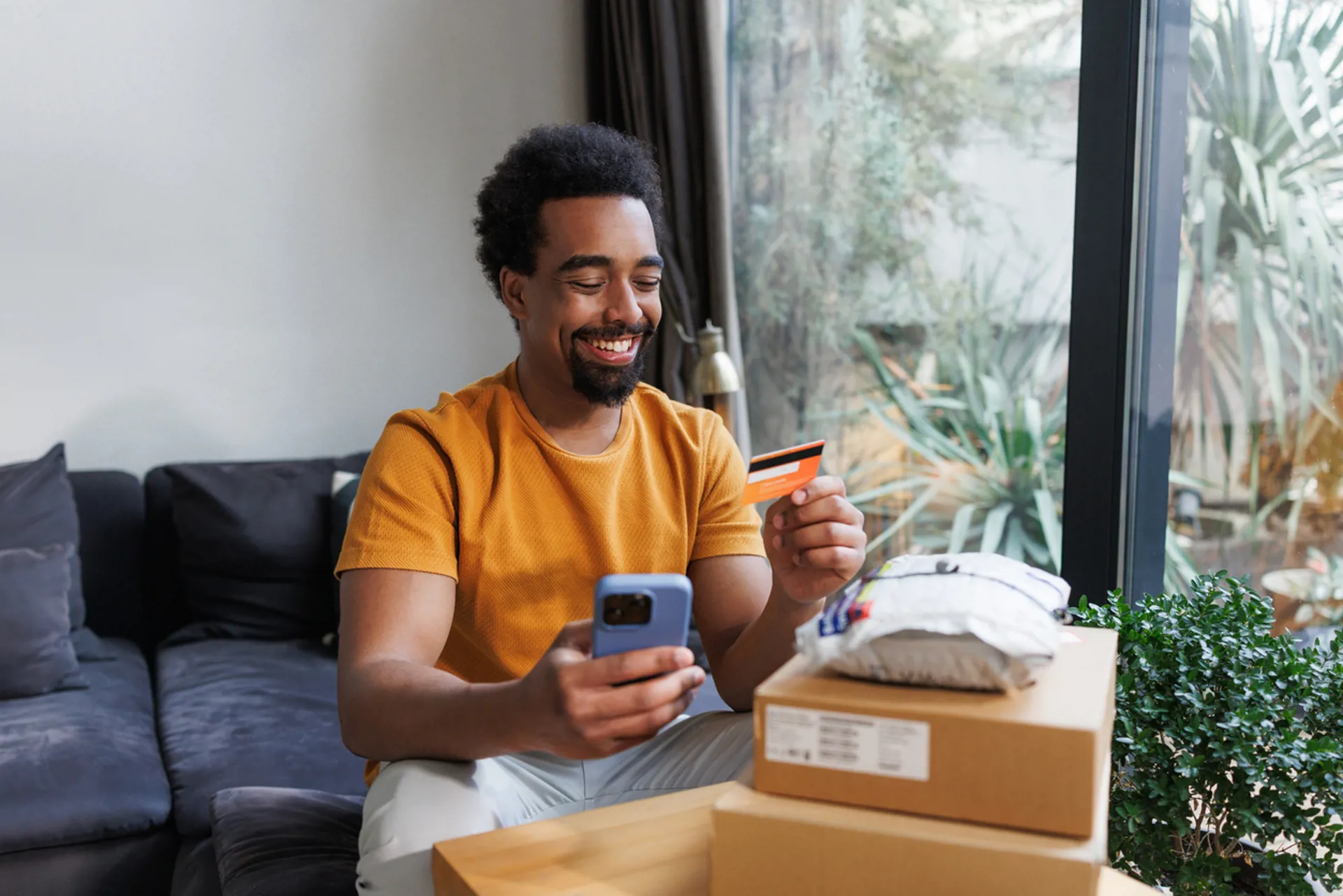 Man enjoying online shopping while unpacking delivered packages at home