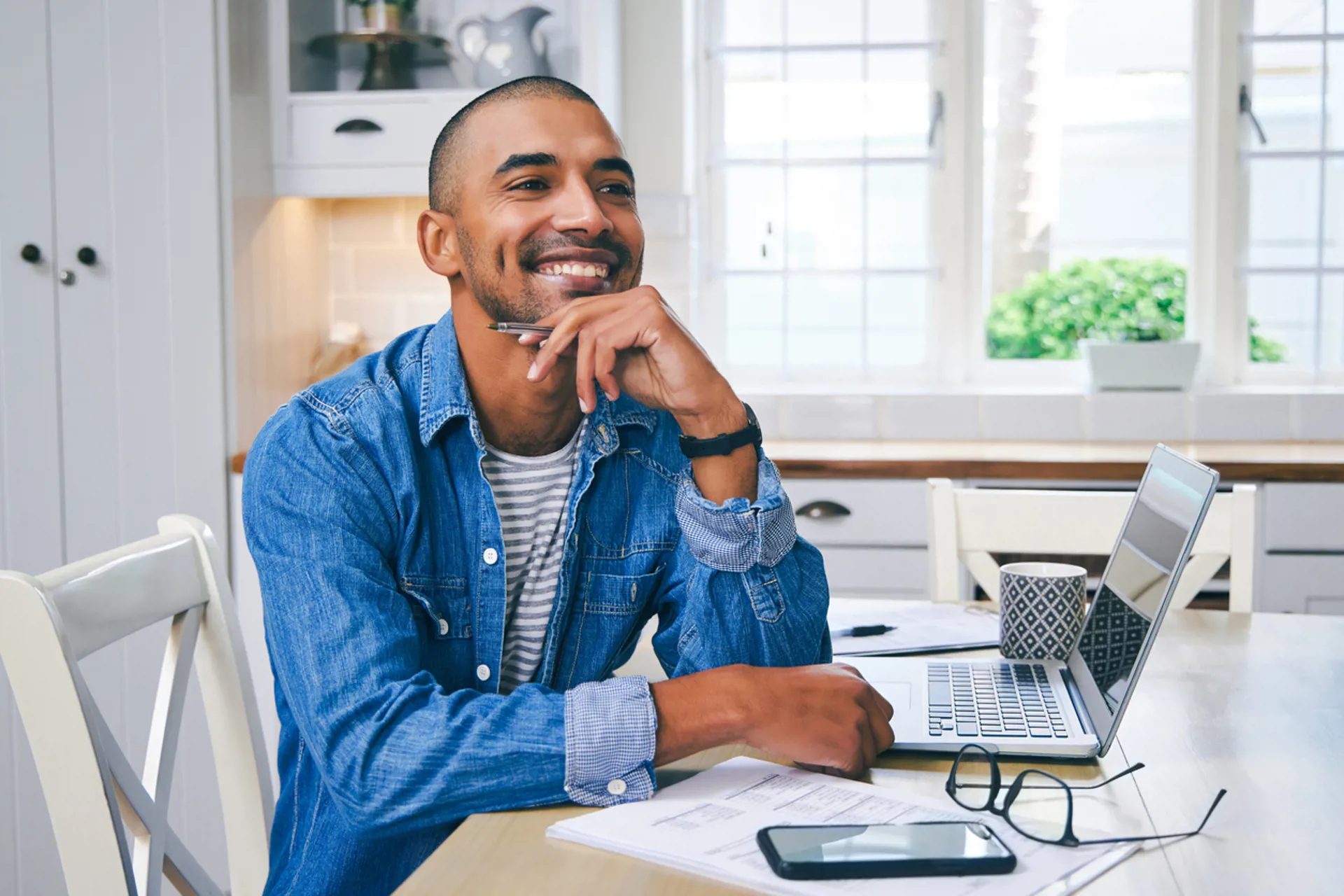 Shot of a young man using a laptop and looking thoughtful while working at home