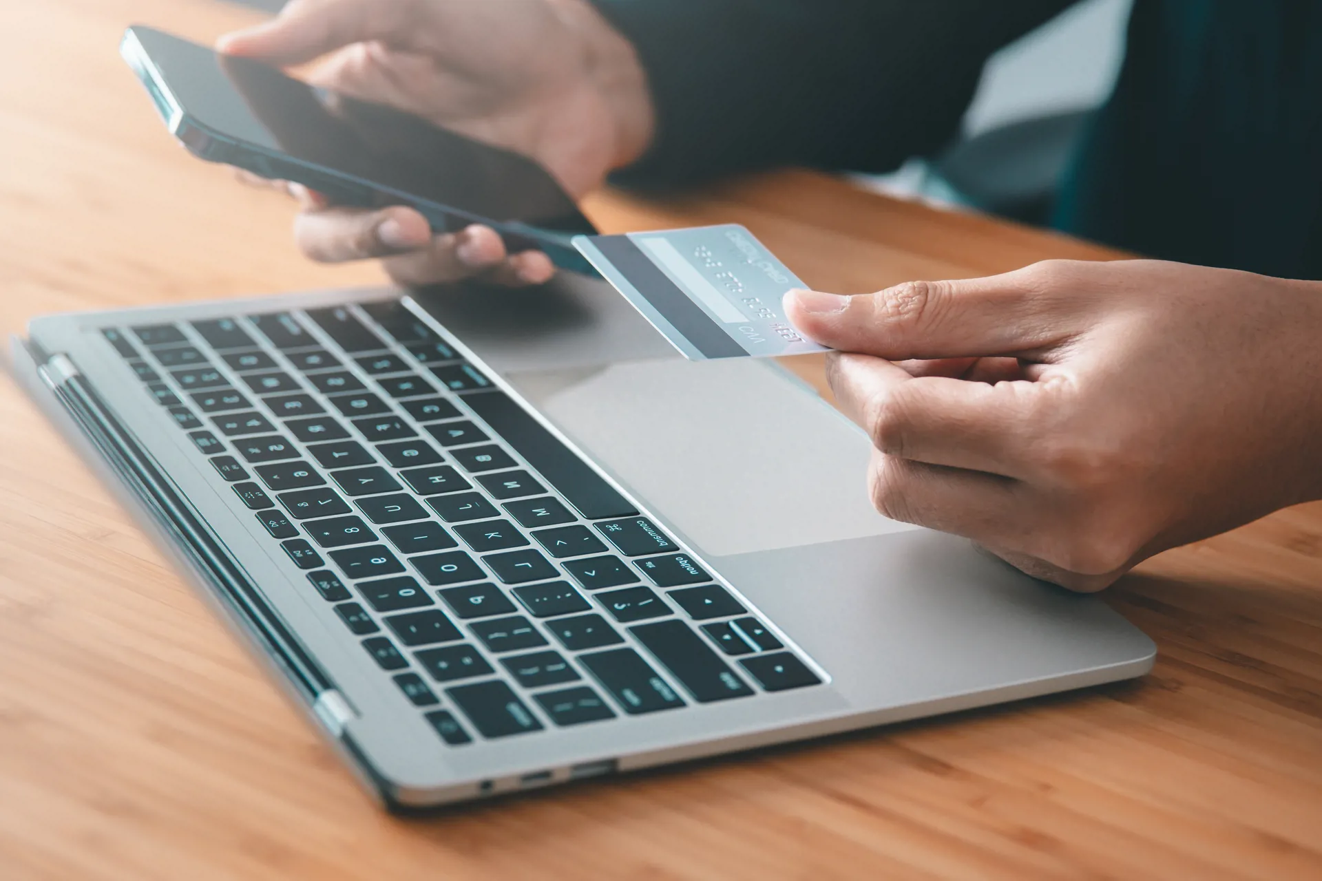 woman with mobile phone and card at laptop