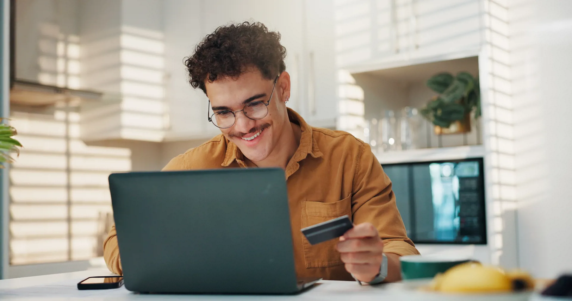 Young man at laptop with card